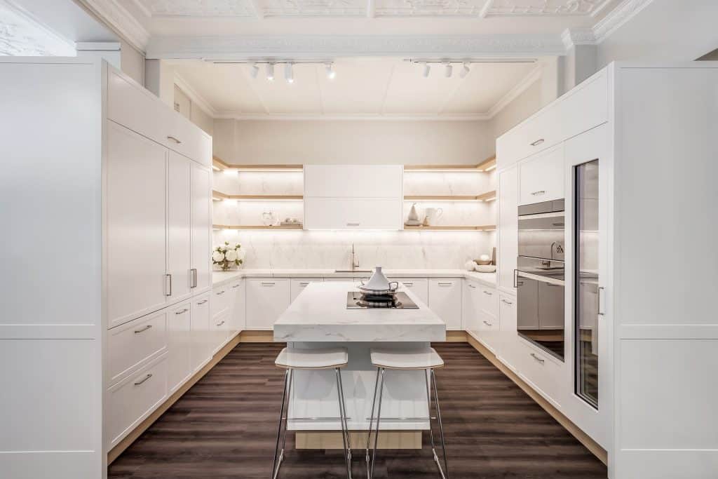 Stunning kitchen renovation in white with contrasting floors.